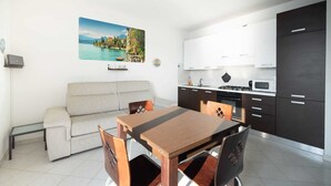 Un espace de vie compact comprenant un canapé, une table à manger et une cuisine moderne.