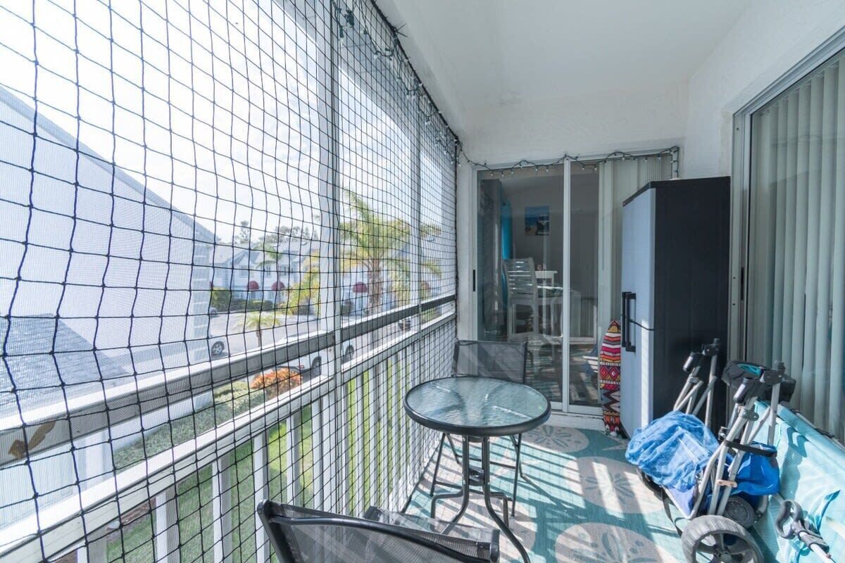 A balcony with a view of the street, a small table, chairs, and a bicycle rack.