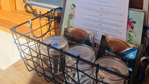 A window with a view of a rural landscape, a wooden door, and a basket with jars and a menu.