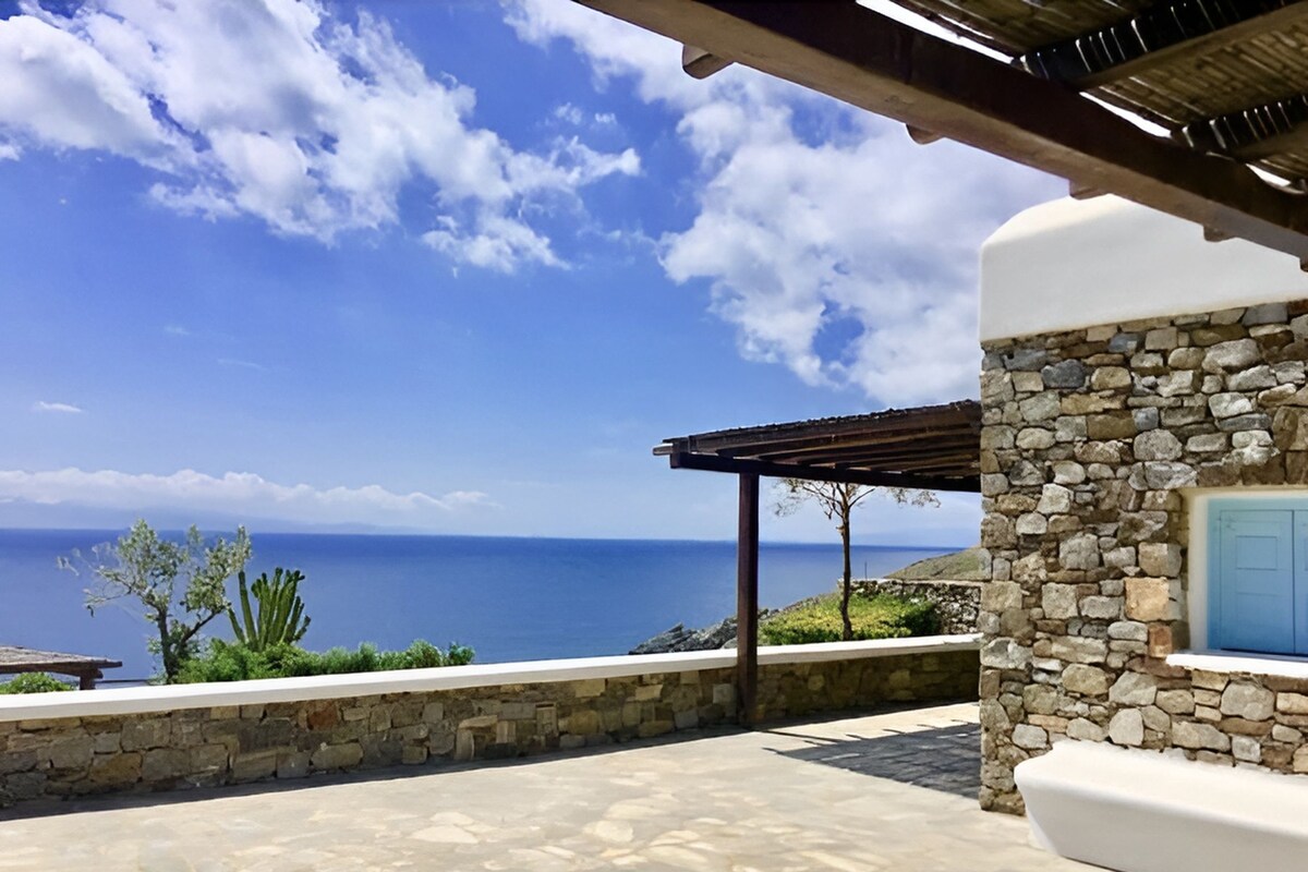 A stone building with a stone wall and a view of the sea.