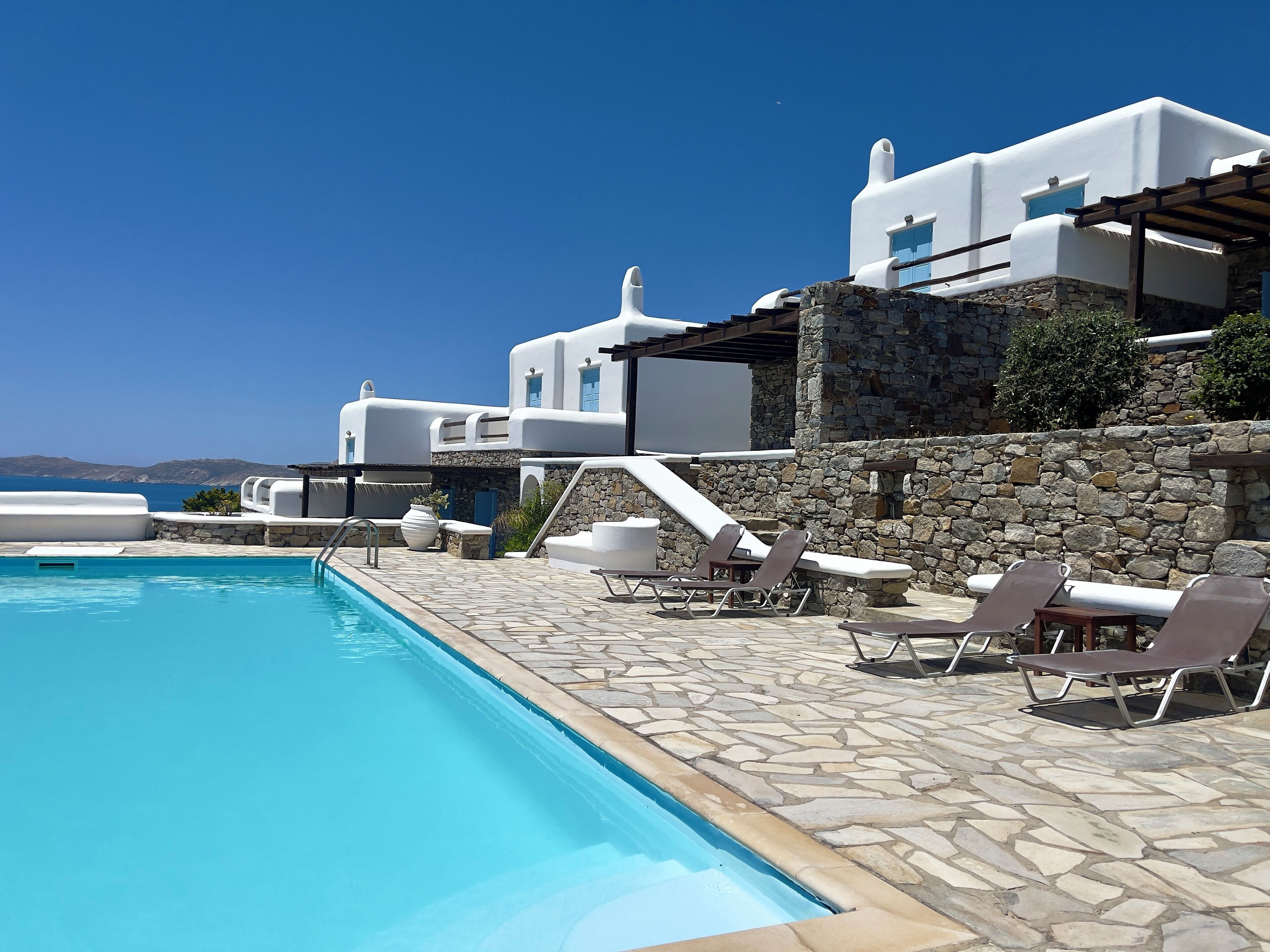 A pool area with lounge chairs and a stone wall.