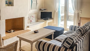 Un salon confortable avec une cheminée, un ensemble de canapés, un téléviseur et une table à manger.