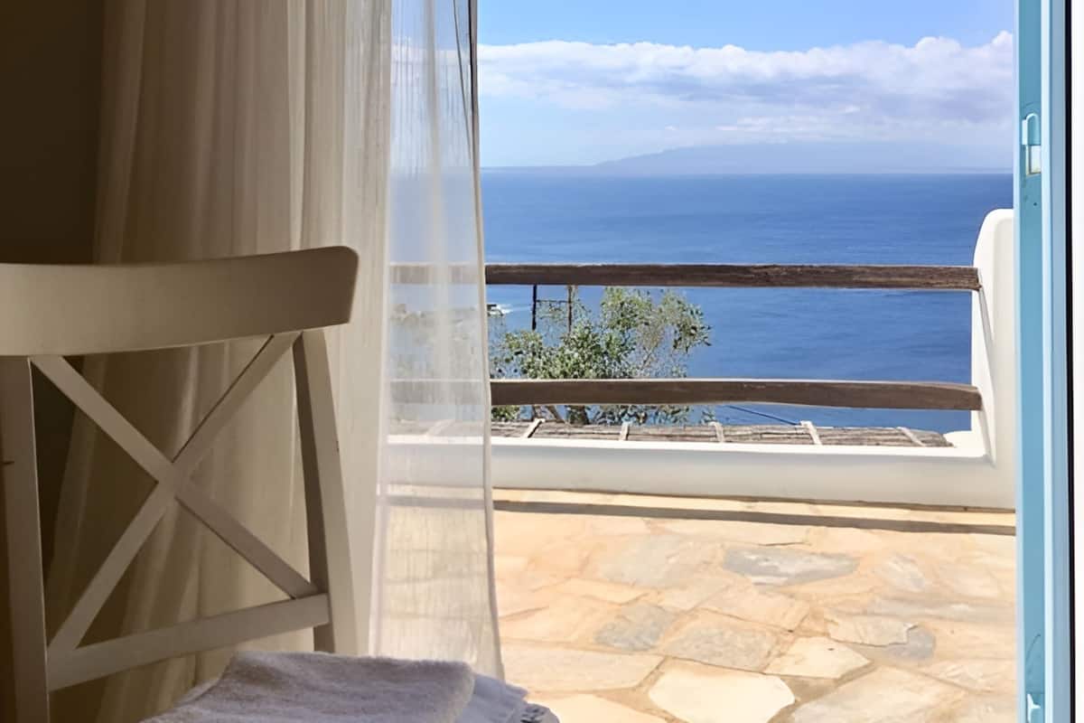 Une pièce avec vue sur la mer, une chaise et un sol en pierre.