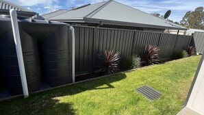 Un edificio residencial con techo gris, antena parabólica y depósitos de agua.