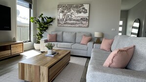 Una sala de estar moderna con un sofá gris, una mesa de centro de madera y un cuadro grande en la pared.