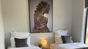Un dormitorio con dos camas, una mesita de noche con lámpara y un cuadro abstracto grande en la pared.