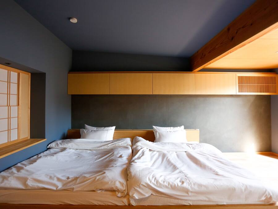 Un dormitorio con cama, cabecero de madera y un divisor japonés corredero.
