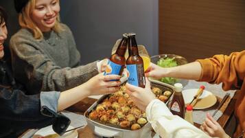 A group of people toasting with beer bottles and glasses, a tray of food, and condiments on a table.