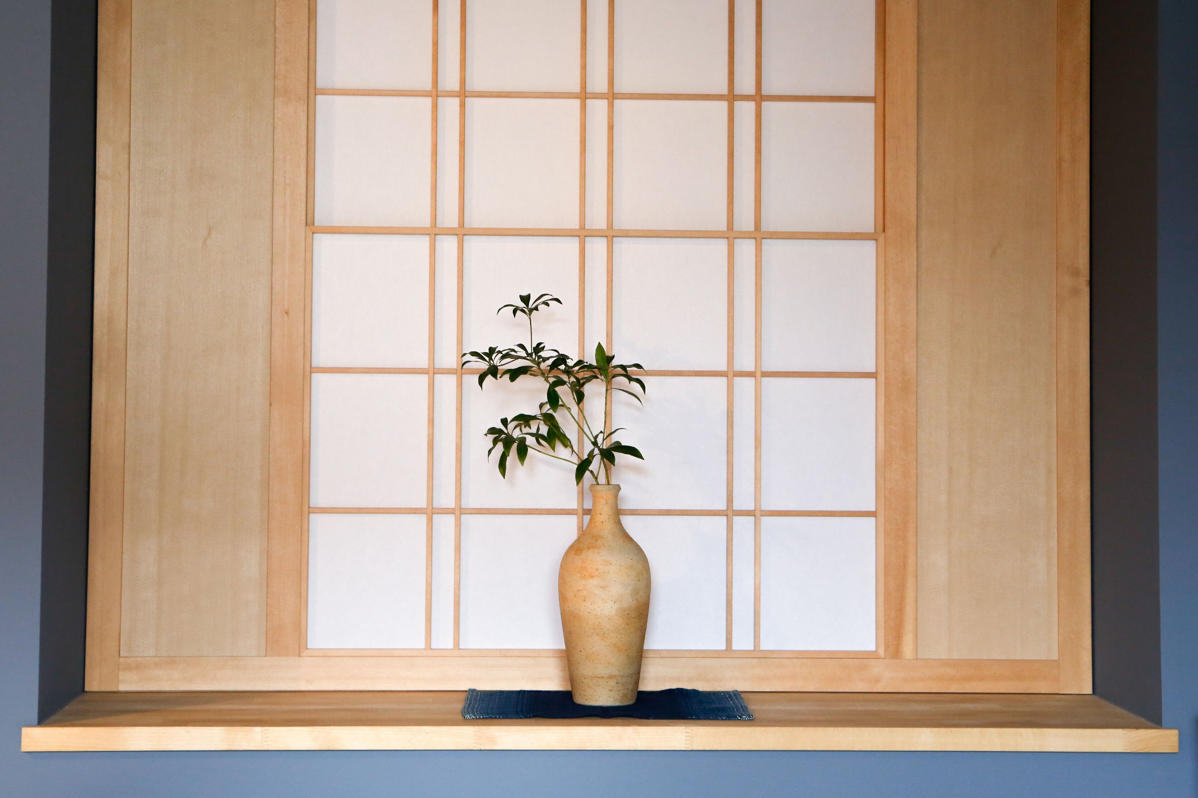 A wooden shelf with a vase containing a plant.