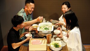 A group of people dining at a table with various dishes and a hot pot.