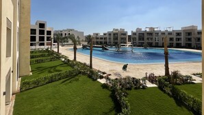 Un complexe hôtelier doté d’une piscine, de palmiers et de bâtiments modernes.