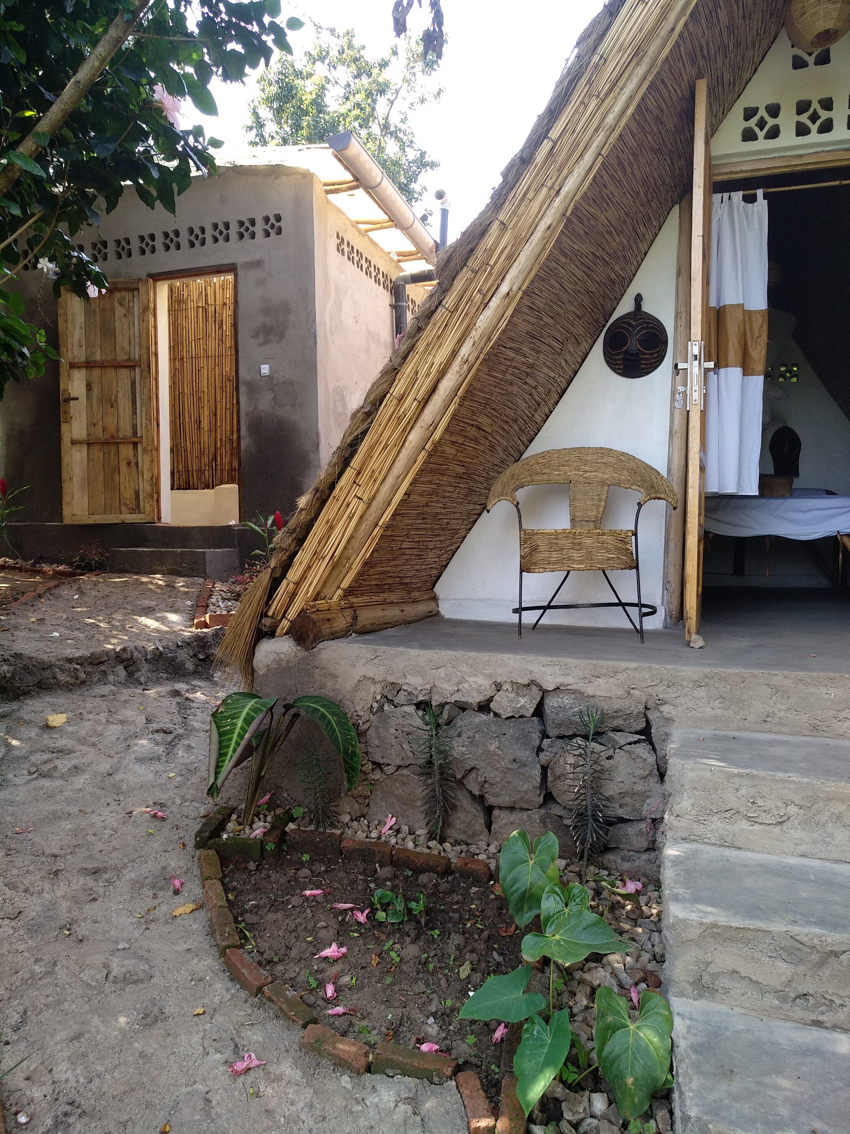 Ein traditionelles Haus mit einem Reetdach, einer Holztür und einem kleinen Garten mit Pflanzen und einer Bank.