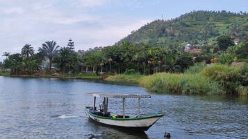 A boat on a calm river with a hilly landscape in the background.