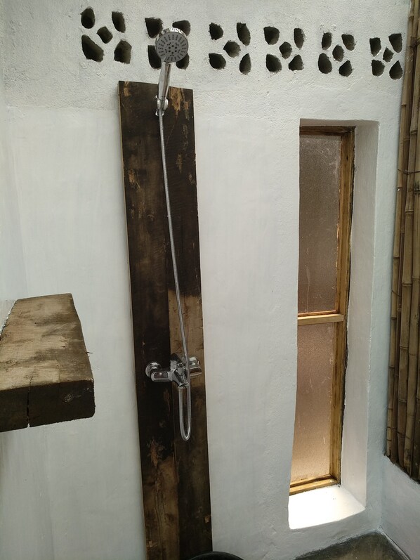 A shower with a wooden door, a small window, and a wall with decorative holes. - INZU Lodge (Nyayumba)