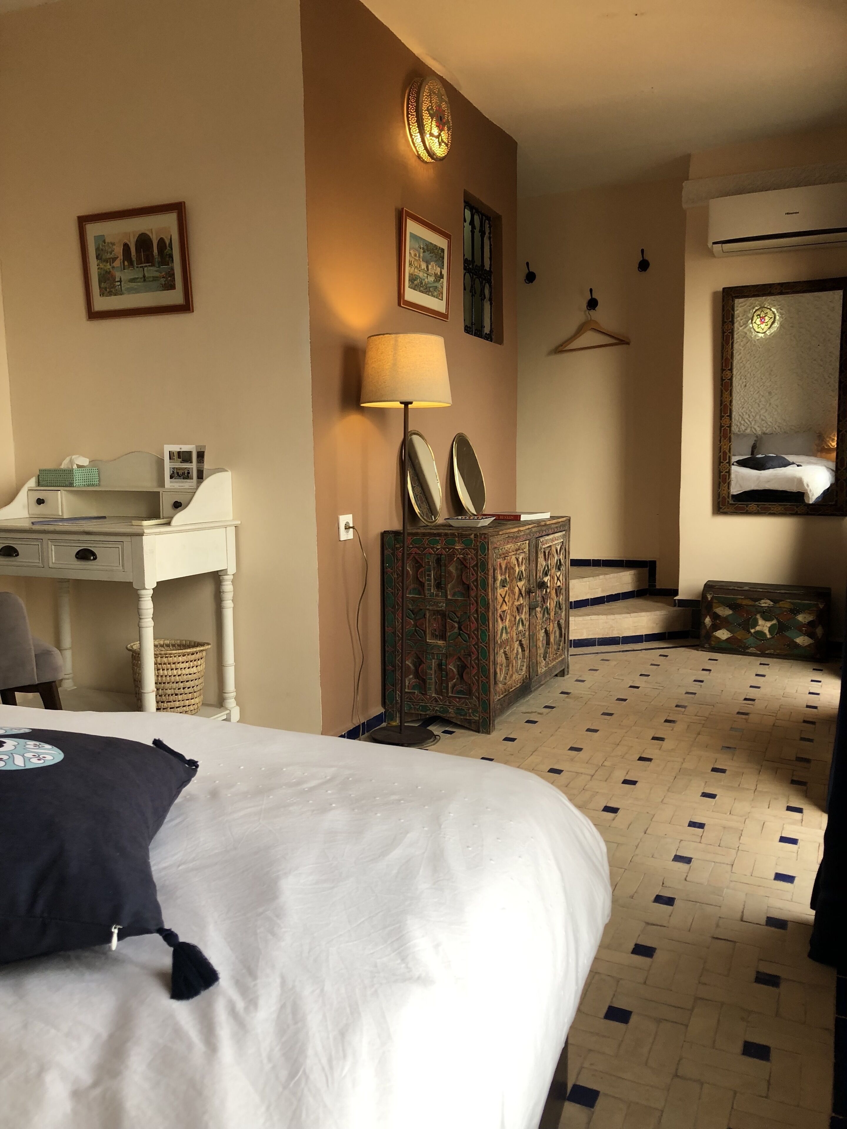 Habitación de hotel con cama, escritorio, cómoda, espejo y aire acondicionado instalado en la pared.