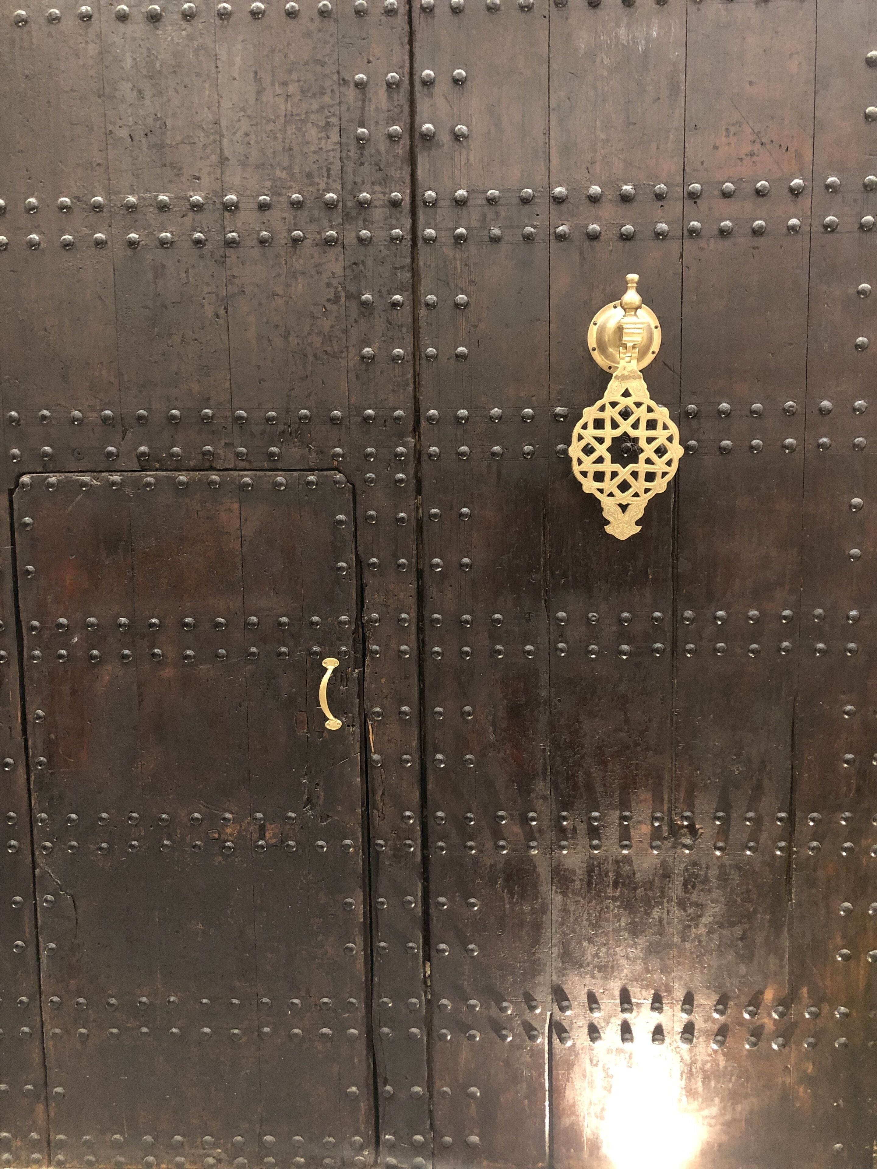 A dark wooden door with metal studs and a brass knocker.