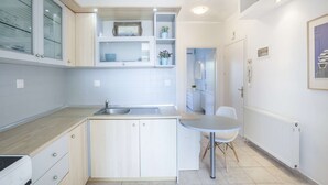 Una cocina compacta con fregadero, armarios y una pequeña mesa de comedor.
