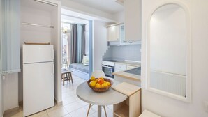 Una cocina compacta con comedor, refrigerador y una mesa con frutero.