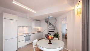A modern kitchen with white cabinetry, a central island, and a spiral staircase.