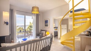 Ein modernes Hotelzimmer mit einem großen Balkon, einer gelben Wendeltreppe und Blick ins Freie.