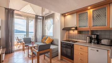 Une cuisine moderne équipée d’une cuisinière, d’un four et d’une machine à café, donnant sur un balcon avec vue sur la mer.