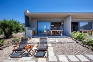 Una casa moderna con un patio que incluye dos sillones de madera y una mesa.