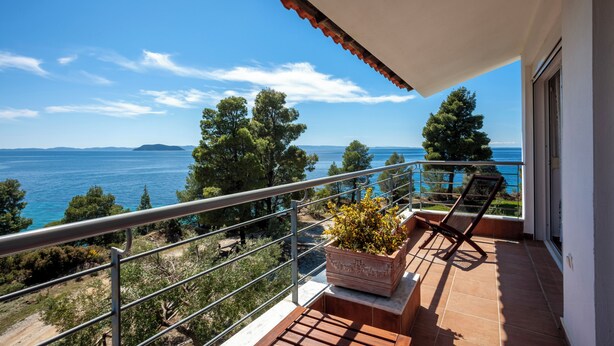 Un balcon avec vue sur la mer, une plante en pot et une chaise.