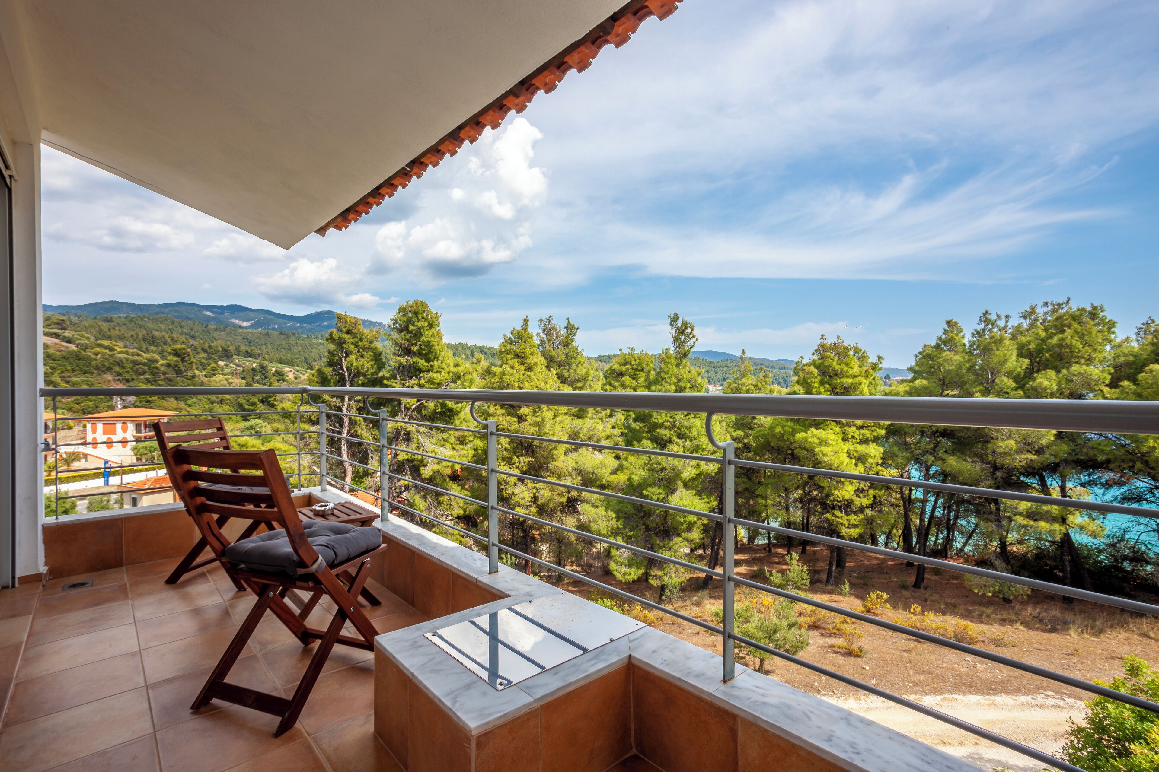 A balcony with a view of a mountainous landscape and a body of water.