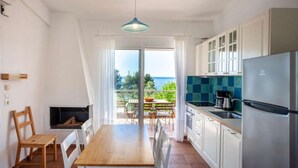 Una cocina moderna con una isla grande, un comedor con vistas y un balcón con mesa y sillas.