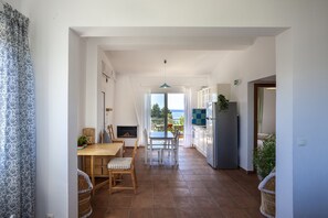 Uma cozinha moderna com área de refeições, vista para o mar e lareira.