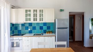 Una cucina moderna con mobili bianchi, uno schienale rivestito di piastrelle blu, un frigorifero in acciaio inossidabile e un tavolo da pranzo in legno.