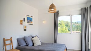 Una camera da letto con un letto, una sedia, una lampada a sospensione e una finestra con tende.