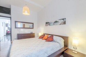 Una camera da letto con un letto, lampade sui comodini, una cassettiera, uno specchio e un quadro appeso al muro.