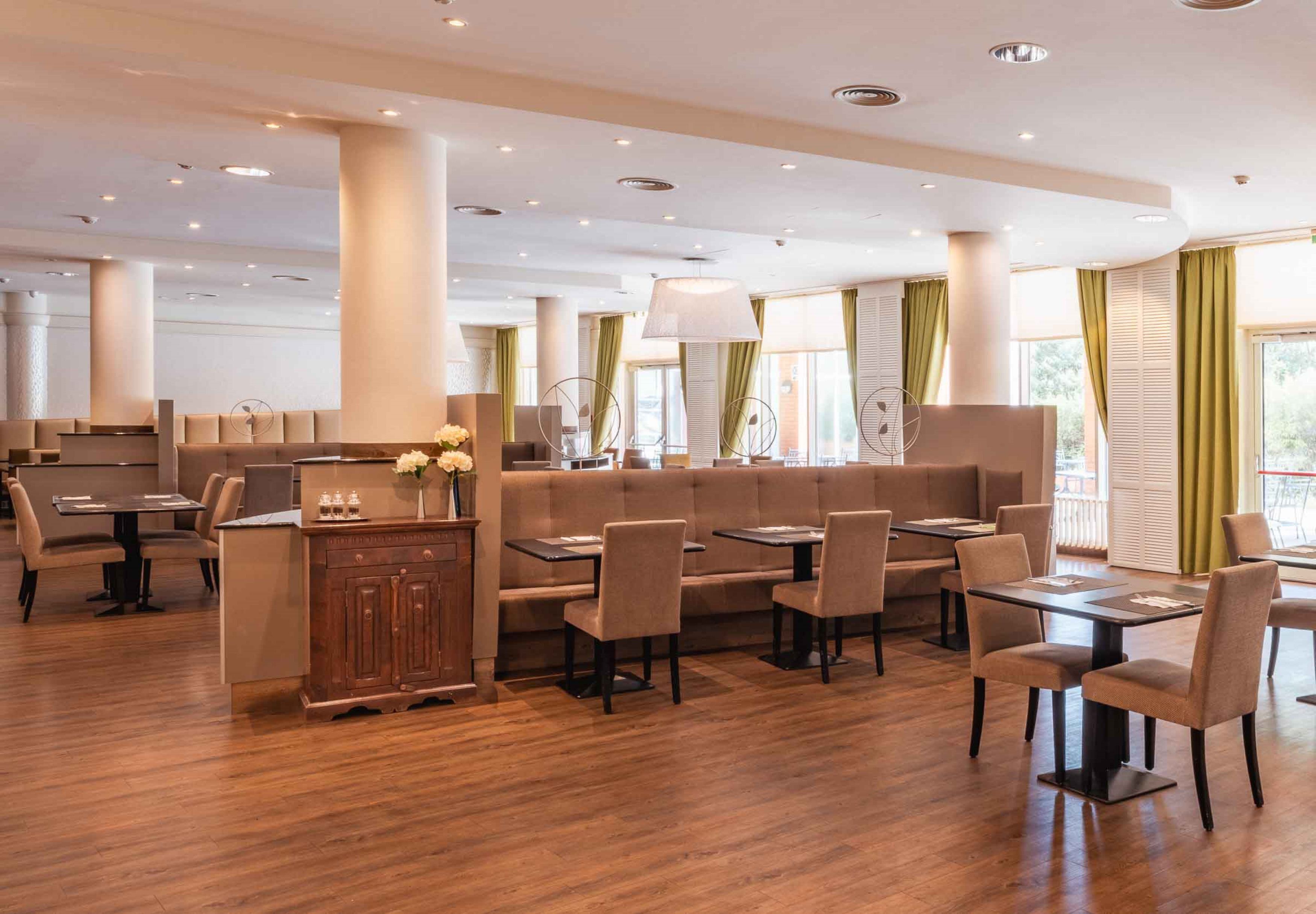 A modern restaurant with high ceilings, recessed lighting, and a mix of booth and table seating.