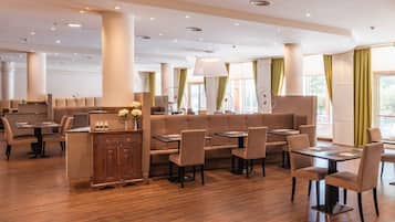 A modern restaurant with high ceilings, recessed lighting, and a mix of booth and table seating.