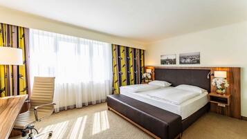Ein Hotelzimmer mit Bett, Schreibtisch, Stuhl und Nachttisch mit Lampe.