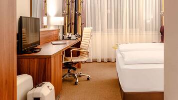 A hotel room with a bed, desk, chair, television, and curtains.