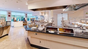 A modern kitchen with stainless steel appliances, a central island, and a view of the outdoors through large windows. - PLAZA Premium Wien (Vienna)