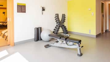 Un gimnasio con una banca, mancuernas y una pelota medicinal.