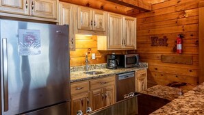 A kitchen with wooden cabinets, stainless steel appliances, granite countertops, and a fire extinguisher.