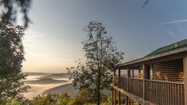 A wooden deck with a railing overlooking a valley.