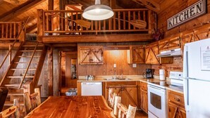 A rustic kitchen with wooden walls and a wooden dining table. - Arkansas Cabin w/ Hot Tub (Ponca)