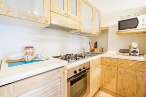A kitchen with wooden cabinets, a gas stove, a microwave, and a coffee maker.