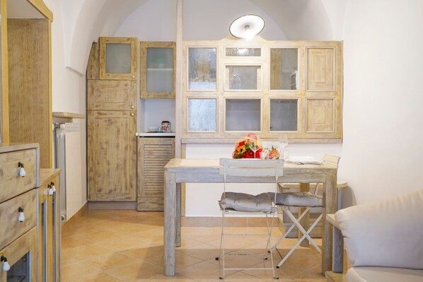 A compact kitchen with wooden cabinets, a dining table, and a chair.