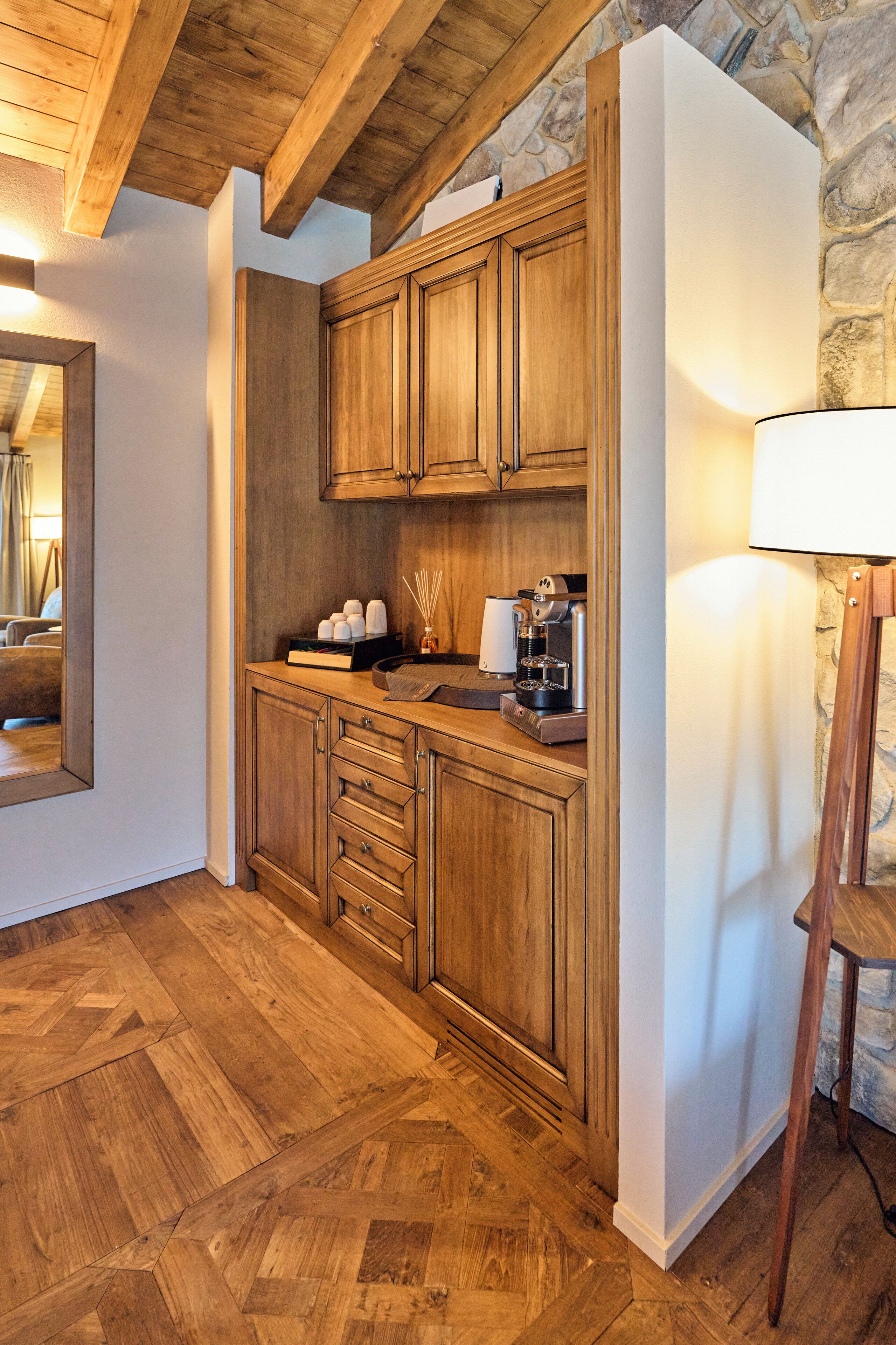 A wooden kitchen with a stone wall, a coffee machine, and a mirror.