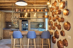Una cocina con armarios de madera, una barra con taburetes y ollas de cobre colgadas en la pared.