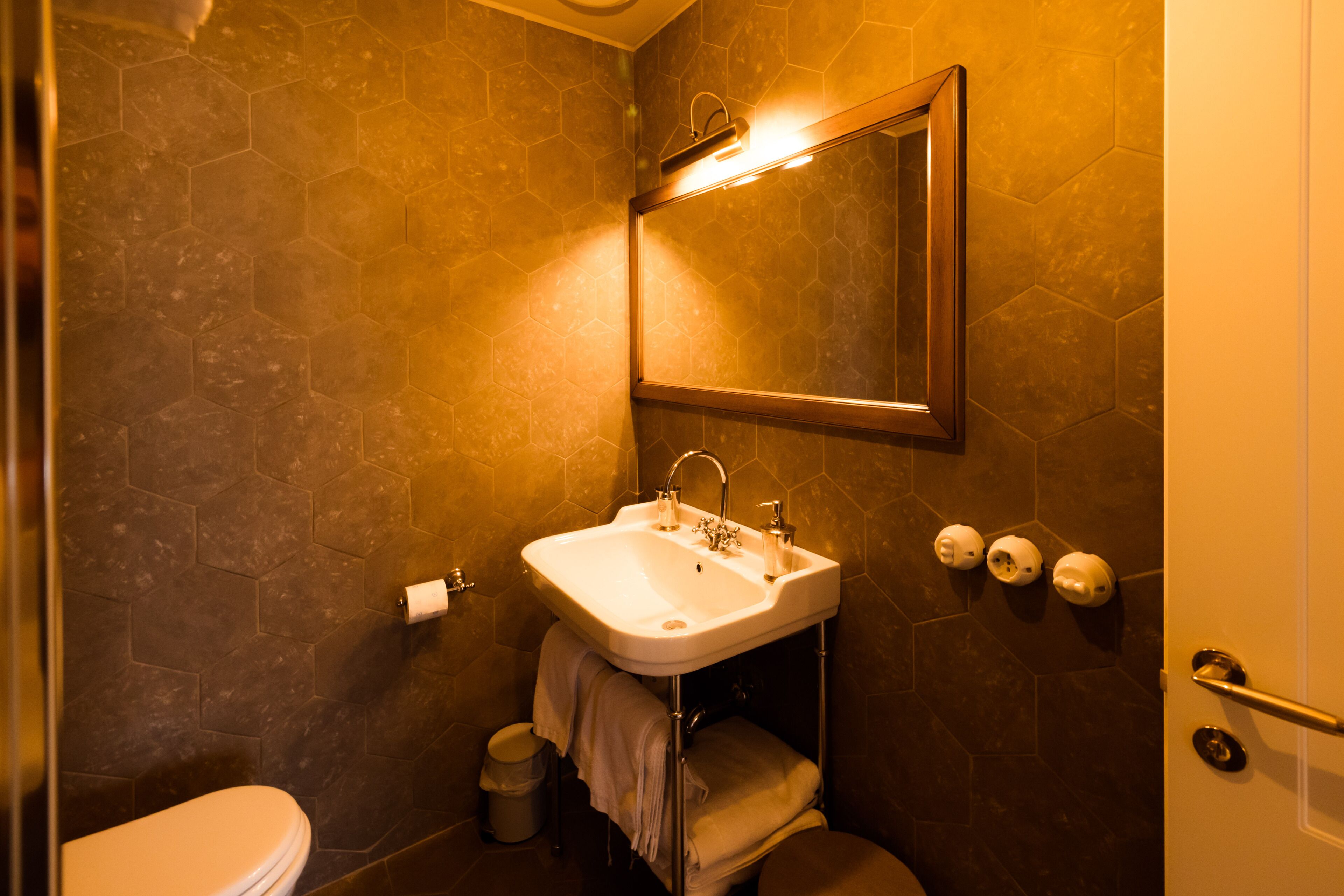 A bathroom with a white sink, a mirror, and a toilet.