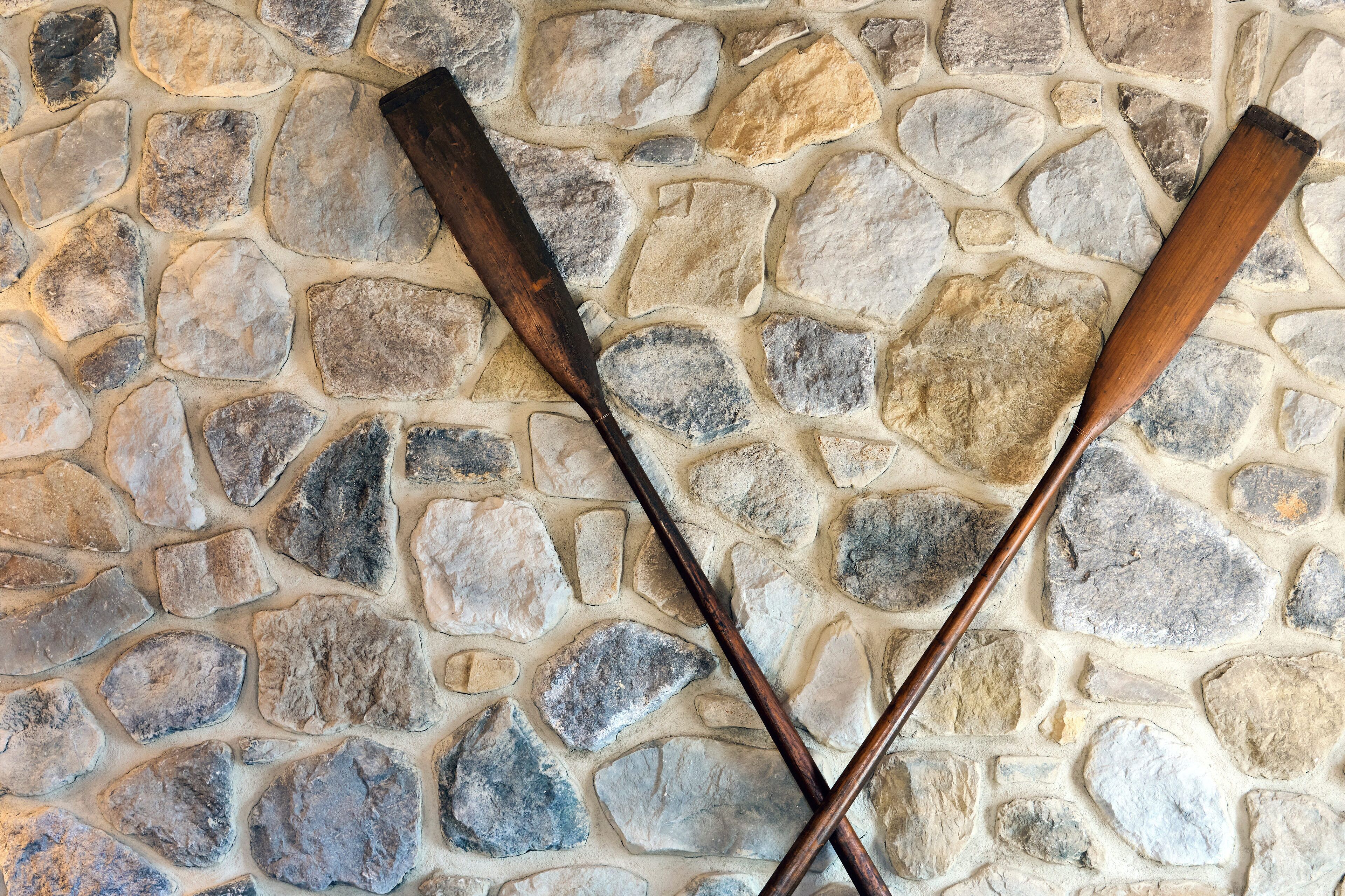 Un mur de pierres sur lequel sont croisées deux battes de baseball en bois.