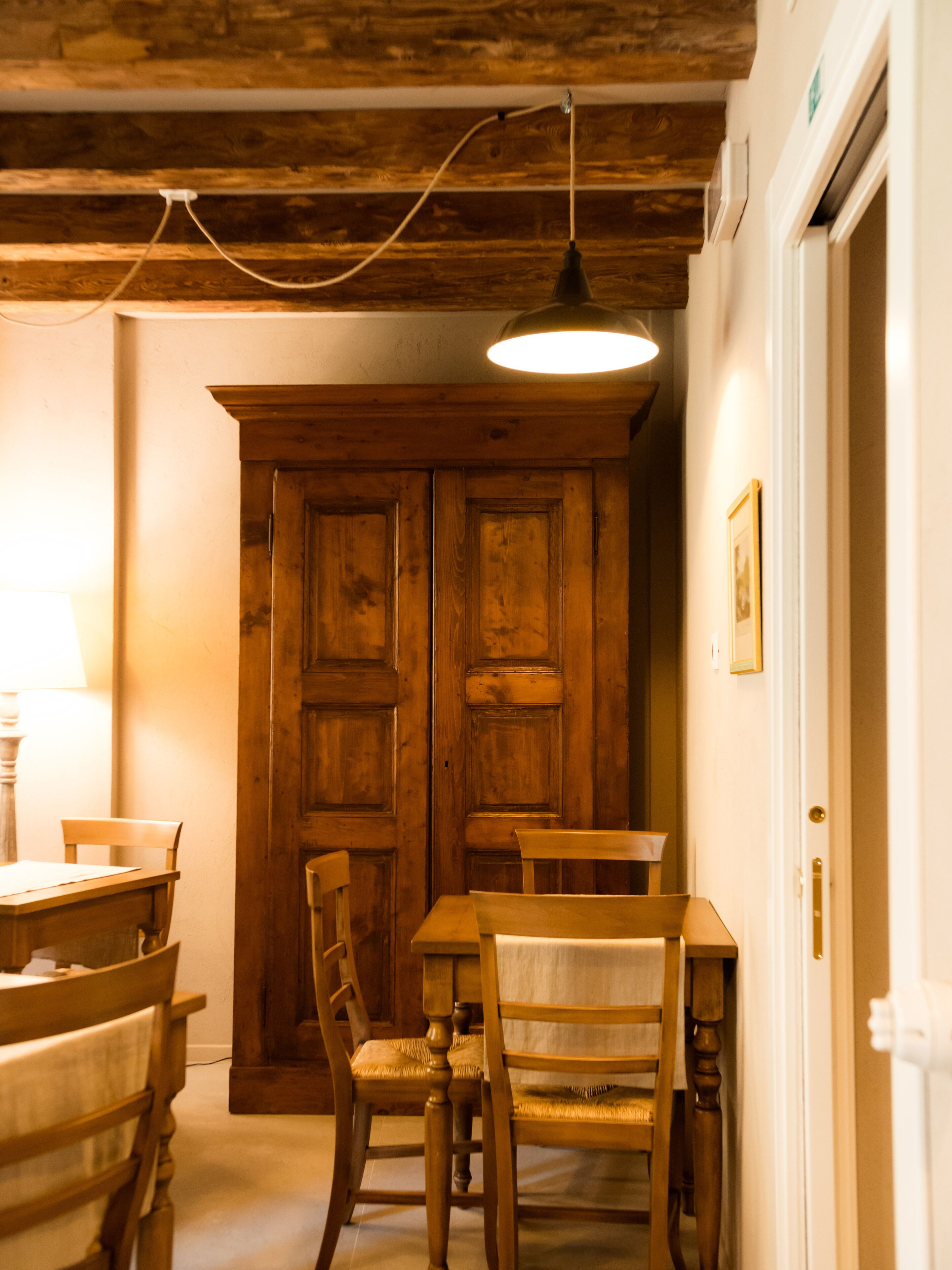 Un comedor con mobiliario de madera, una mesa, sillas y una lámpara colgante.