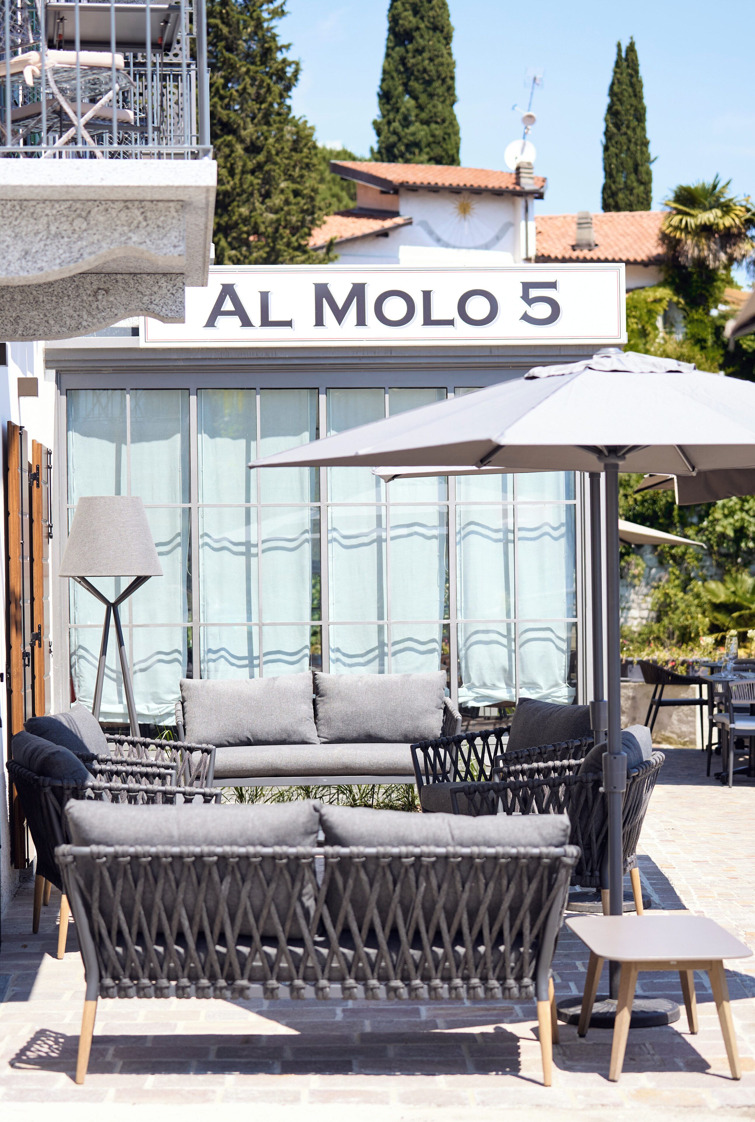An outdoor seating area with wicker furniture and a sign reading "AL MOLO 5".